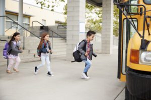 Three elementary children walking from school to a school bus