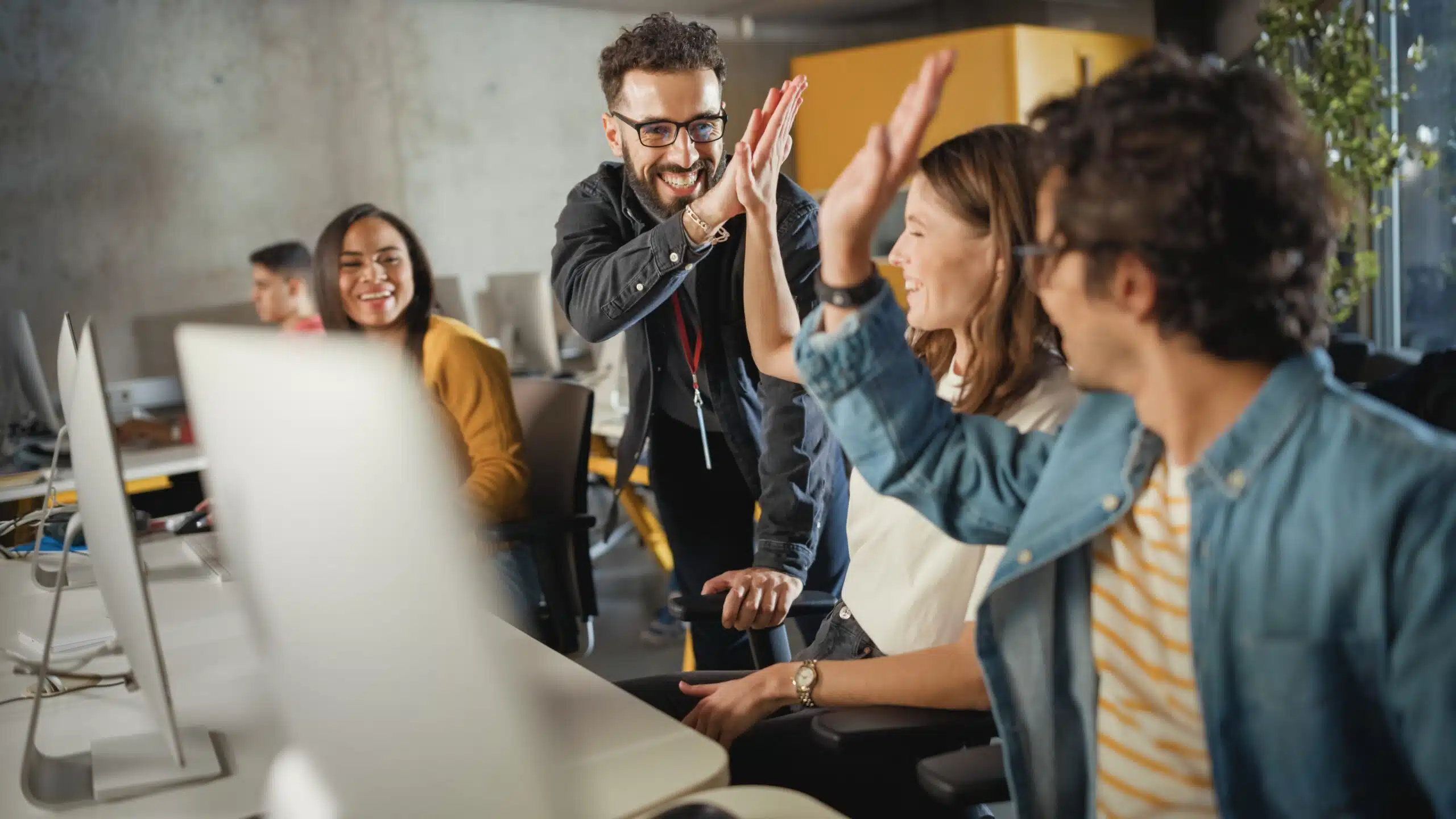 Male teacher giving high school students a high-five in a computer lab