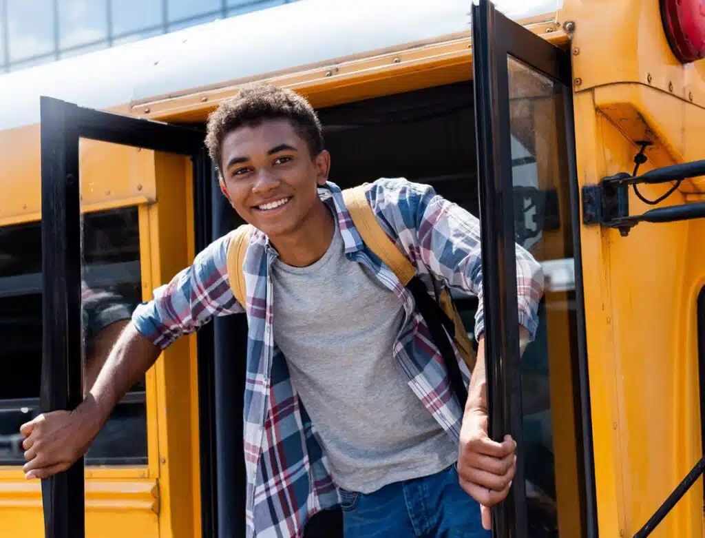 Teen boy smiling as he exits school bus