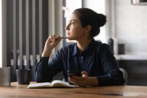 Woman sitting at desk looking thoughtfully to the side