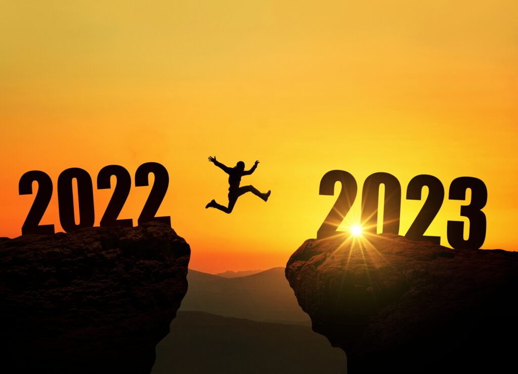 Silhouette of a man jumping from a cliff with 2022 above it to another cliff with 2023 above it