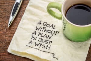 Coffee cup sitting atop a napkin that reads "A goal without a plan is just a wish."