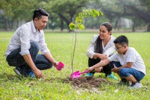 Man and woman helping boy plant a tree