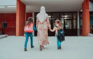 Mother and two children walking into school