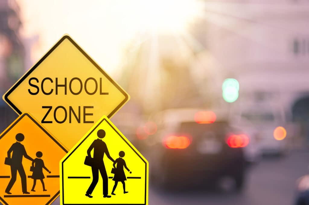 Yellow signs reading, "SCHOOL ZONE" and showing silhouette of parent holding child's hand