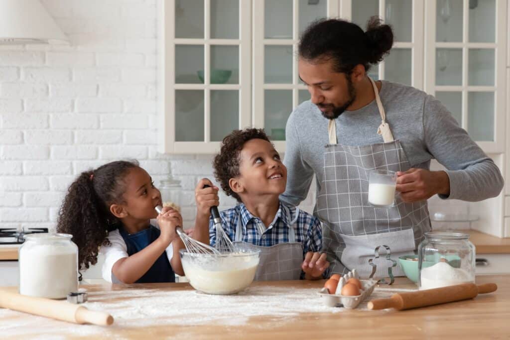Father mixing ingredients in the kitchen with young boy and girl