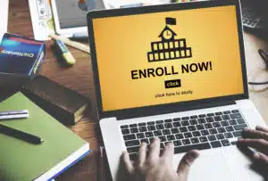 Laptop with drawing of a school and the words "Enroll Now"