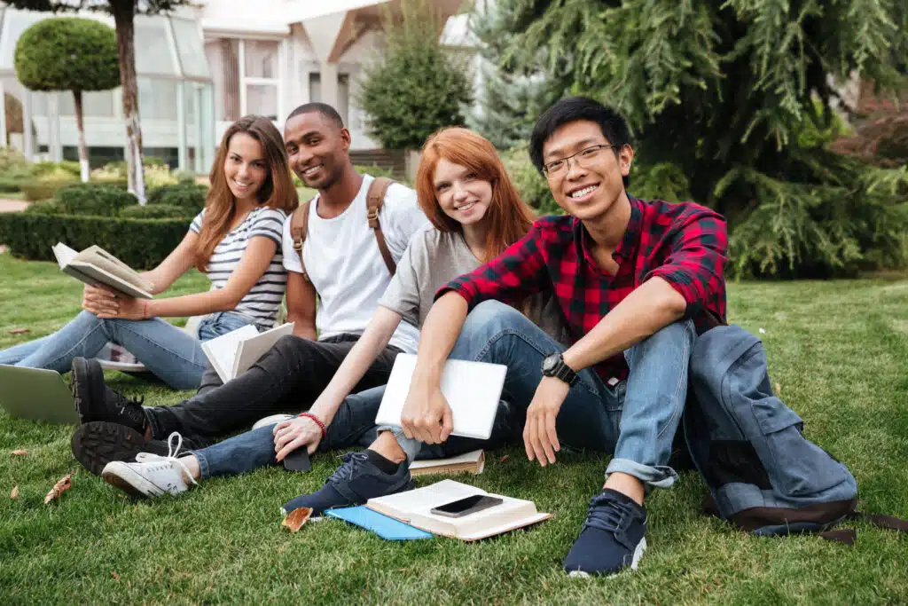 Four teenagers sitting on grass together in front of school