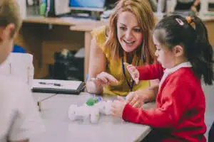 Female teacher working with young girl on a robotics task