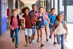 Group of children wearing backpacks running in the school halls