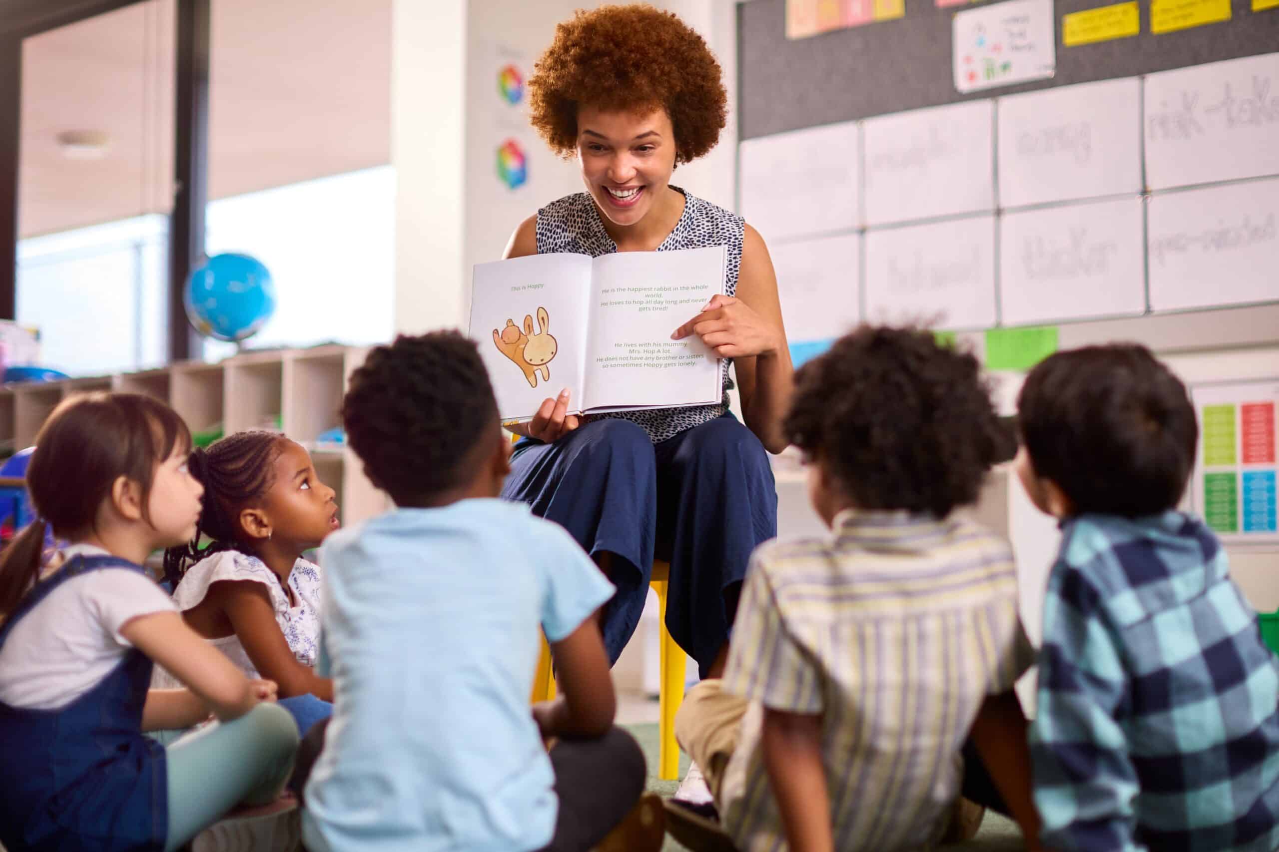 Smiling teacher reading to a group of young students