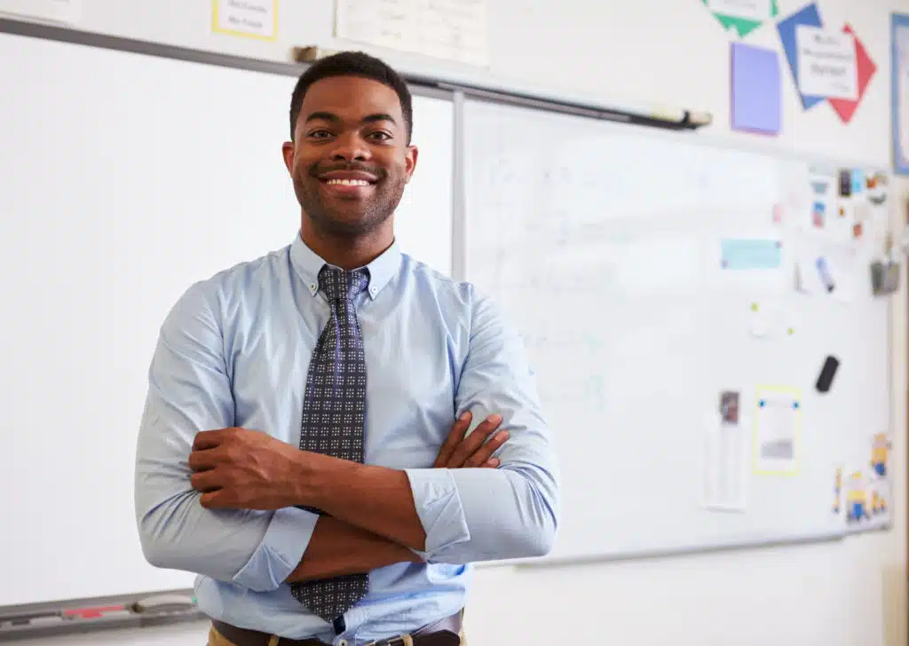 Smiling male teacher standing in front of classroom