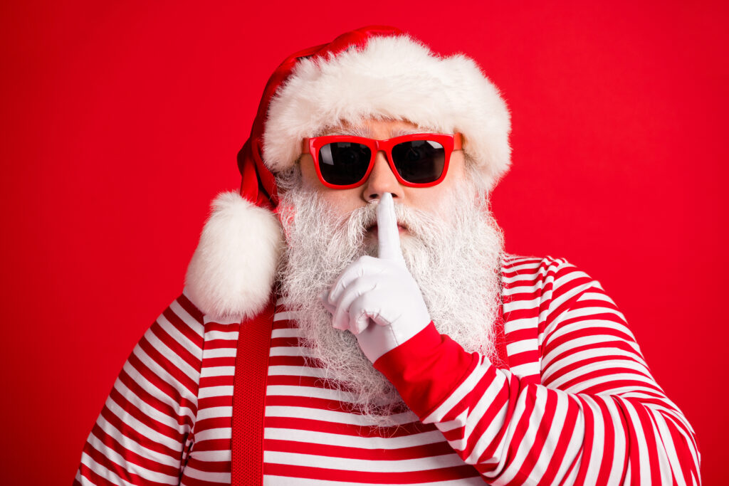 Santa wearing glasses and holding a figure to his mouth.